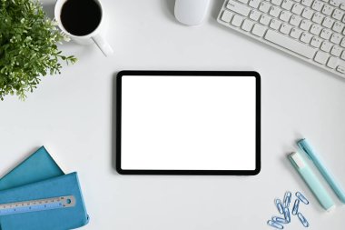 Tablet, kahve ve kırtasiyeli minimalist beyaz ofis masası..