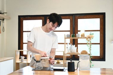 Bir adam kahve öğütücüsünde kahve çekirdeklerini öğütüyor. Kahve öğütücüsü ahşap bir masanın üzerinde...