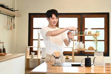 Bir adam kahve öğütücüsünde kahve çekirdeklerini öğütüyor. Kahve öğütücüsü ahşap bir masanın üzerinde...