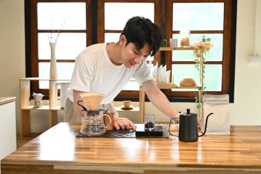 Bir adam mutfakta kahve yapıyor. Gülümsüyor ve süreçten zevk alıyor gibi görünüyor..