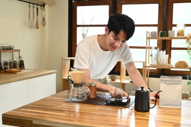 Bir adam mutfakta kahve yapıyor. Gülümsüyor ve sürecin tadını çıkarıyor..