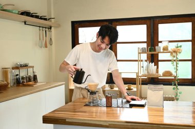 Bir adam fincana kahve dolduruyor. Kahve sade bir kahve demliğinden dökülüyor. Adam kahveyi koyarken gülümsüyor...