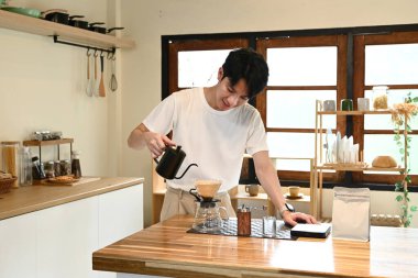 Bir adam fincana kahve dolduruyor. Kahve sade bir kahve demliğinden dökülüyor. Adam kahveyi koyarken gülümsüyor...