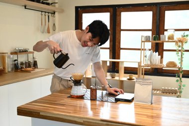 Bir adam fincana kahve dolduruyor. Kahve sade bir kahve demliğinden dökülüyor. Adam kahveyi koyarken gülümsüyor...