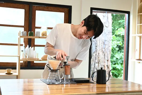 Bir adam mutfakta kahve yapıyor. O bir fincana kahve dolduruyor ve beyaz bir gömlek giyiyor...