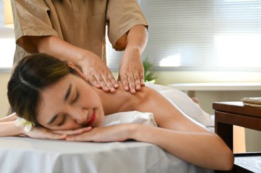 Bir kadın masaj terapistinden masaj yaptırıyor. Kadın gülümsüyor ve masajın tadını çıkarıyor. Bir masaj terapisti sırtına masaj yapıyor..