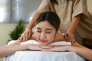 Bir kadın masaj terapistinden masaj yaptırıyor. Kadın gülümsüyor ve masajın tadını çıkarıyor. Bir masaj terapisti sırtına masaj yapıyor..