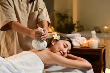Derin rahatlama için sıcak bitkisel top ile vücut masajı. Spa salonunda masaj yaptıran bir kadın..