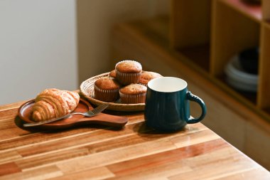 Bir tabak kek ve bir fincan kahve ahşap bir masada oturur. Çörekler sepsiyonda, kahve fincanda...
