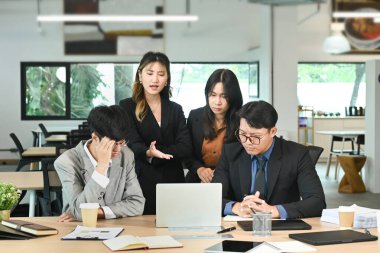 İş adamları ofiste dizüstü bilgisayar kullanarak ciddi bir toplantı yapıyorlar..