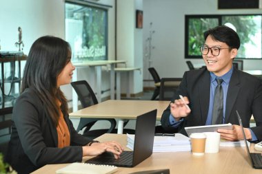 Dizüstü bilgisayarda çalışan iki mutlu yönetici toplantıda mali belgeleri tartışıyor...