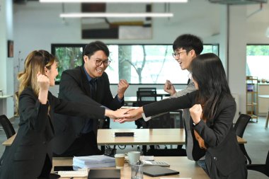 İş dünyasındaki bir grup işçi takım çalışmasını ve birliği göstermek için el ele tutuşuyor. İnsanlar işbirlikçi atmosfer öneriyor..