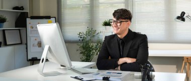 Takım elbiseli bir adam önünde bir bilgisayar monitörüyle masada oturuyor. Gülümsüyor ve işinden zevk alıyor. Profesyonellik ve verimlilik kavramı