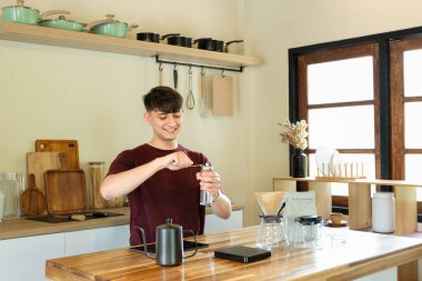 Bir adam kahve öğütücüsünde kahve çekirdeklerini öğütüyor. Kahve öğütücüsü ahşap bir masanın üzerinde...