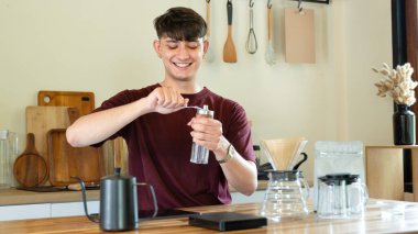 Bir adam kahve öğütücüsünde kahve çekirdeklerini öğütüyor. Kahve öğütücüsü ahşap bir masanın üzerinde...