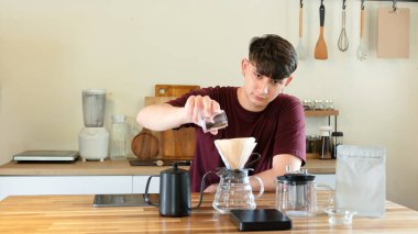 Adam sabah ışığında minimalist mutfakta manuel kahve yapıyor..