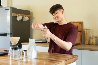 Bir adam kahve öğütücüsünde kahve çekirdeklerini öğütüyor. Kahve öğütücüsü ahşap bir masanın üzerinde...