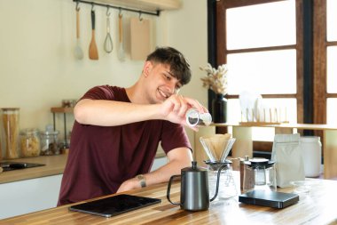 Adam sabah ışığında minimalist mutfakta manuel kahve yapıyor..