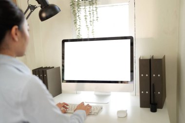 Önünde bilgisayar monitörü olan bir kadın masada oturuyor. Monitör boş ve klavyeye yazı yazıyor. Verimlilik ve odaklanma kavramı