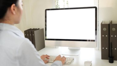 Önünde bilgisayar monitörü olan bir kadın masada oturuyor. Monitör boş ve klavyeye yazı yazıyor. Verimlilik ve odaklanma kavramı.