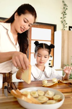 Bir anne, genç bir kıza mutfakta nasıl sandviç yapılacağını öğretiyor..
