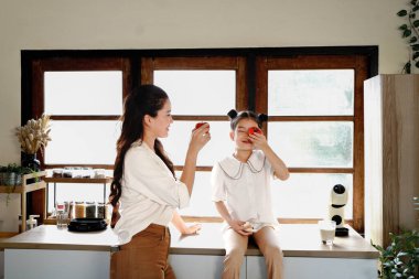 Bir anne ve bir çocuk mutfakta kırmızı domatesle oynuyorlar. Mutlu bir aile zamanı..