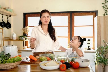 Anne kızı mutfak yemeği pişiriyor, çocuk pişiriyor, mutlu kızı bir araya getiriyor, evde ebeveynlik yapıyor..