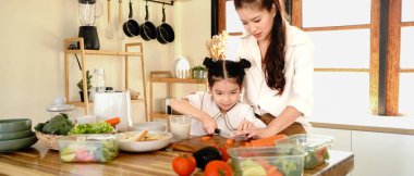 Anne ve mutlu kız, küçük bir çocuğun evde yemek tarifi öğrendiği bir aile olarak mutfakta salata yapıyorlar. salata pastası, kesim ya da anne çocuk gelişimi için kızına yemek pişirmeyi öğretiyor..