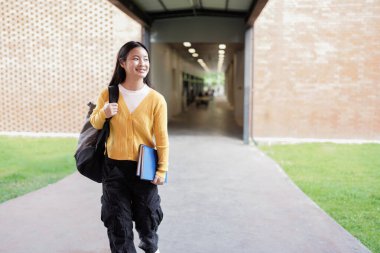Sırt çantası ve planlayıcısı okul kampüsünde duran gülümseyen lise öğrencisinin portresi..