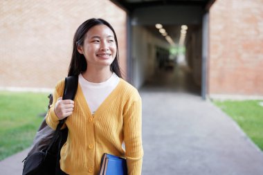 Elementary school student walking down a bright school hallway, heading back to class after enjoying recess, carrying a backpack and embracing the joy of learning.