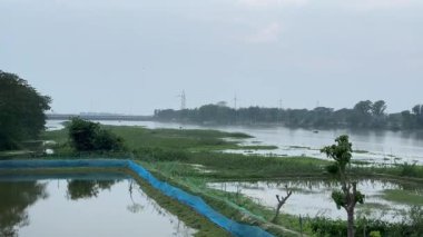 Hindistan 'ın kırsal kesimlerinde tarım arazileri olan sakin nehir manzarası Hindistan' ın kırsal kesimlerinde akan bir nehrin huzurlu manzarası..