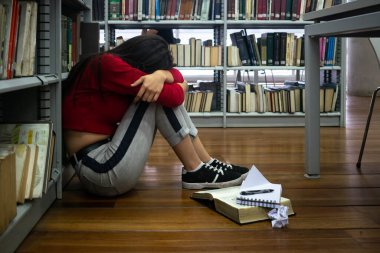 Hüsrana uğramış, depresyonda ve üzgün genç bir kız kütüphanede. Stres çalış