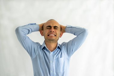 Stresli, çaresiz ve sıkıntılı bir adam elleri başının üstünde kötü bir baş ağrısı hissediyor.