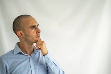 Genç işadamı elini çenesine koyup yukarı bakarken geleceğini ve iş planlarını düşünüyor, düşünüyor ve planlıyor.