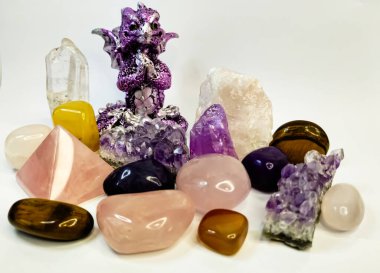 Figurine of purple Dragon sitting in the Buda pose and prays for the well-being of all people in the New Year under the rule of the Dragon. It sits surrounded by treasures, precious crystals: amethyst, rose quartz, auric quartz clipart