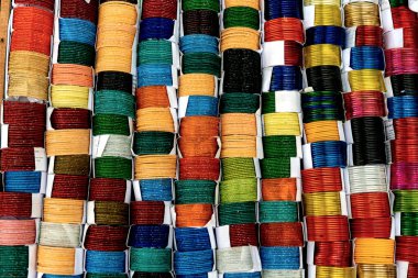 Değişik renklerde geleneksel bileziklerin canlı ve simetrik deseni, düzenli bir şekilde sıralanmış. Çoğunlukla cam, metal veya plastikten yapılmış bu dekoratif bilezikler, özellikle Hindistan ve Bangladeş 'te, Güney Asya kültürlerinde popülerdir..