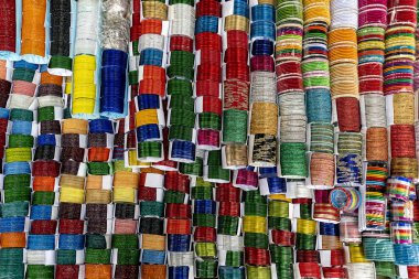 Değişik renklerde geleneksel bileziklerin canlı ve simetrik deseni, düzenli bir şekilde sıralanmış. Çoğunlukla cam, metal veya plastikten yapılmış bu dekoratif bilezikler, özellikle Hindistan ve Bangladeş 'te, Güney Asya kültürlerinde popülerdir..