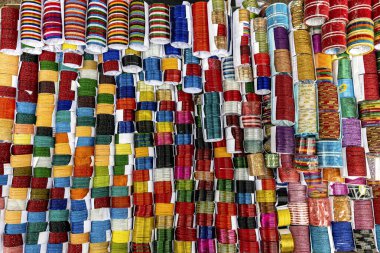 Değişik renklerde geleneksel bileziklerin canlı ve simetrik deseni, düzenli bir şekilde sıralanmış. Çoğunlukla cam, metal veya plastikten yapılmış bu dekoratif bilezikler, özellikle Hindistan ve Bangladeş 'te, Güney Asya kültürlerinde popülerdir..