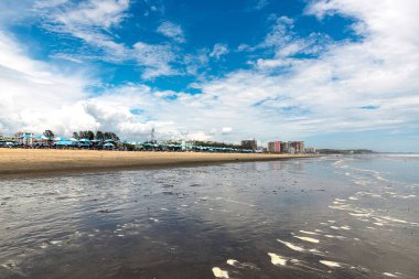 Ziyaretçiler rahatlar ve parçalı bulutlu bir gökyüzünün altında Coxs Bazar, Bangladeş 'teki geniş kumlu plajda oynarlar..
