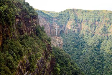 Hindistan 'ın Meghalaya kentindeki Cherrapunjee (Sohra) yakınlarındaki Wah-Kaba Şelalesinin görkemli manzarası. Bu yüksek şelale, sarp bir uçurumdan, yemyeşil tepeler ve sisli gökyüzüyle çevrili derin bir vadiye dramatik bir şekilde dalıyor..