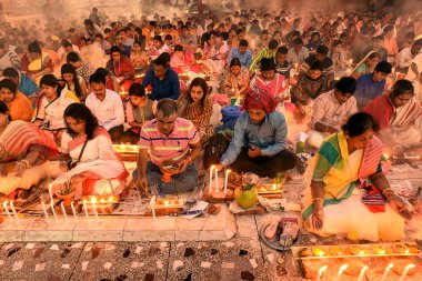 İnsanlar mum ışığında dumanla ve loş ışıkla çevrili bir dua toplantısına katılıyorlar. Bağlılık ve ruhanilikle dolu huzurlu bir atmosfer yaratıyorlar..