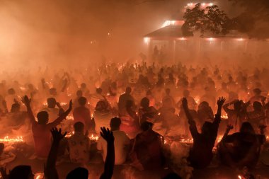 Katılımcılar, bu canlı gece kutlamasında parlayan mumlar, duman ve topluluk hissi arasında neşeli bir törene katılıyorlar. Atmosfer bağlılık ve birlik ile dolu..