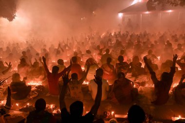 Katılımcılar, bu canlı gece kutlamasında parlayan mumlar, duman ve topluluk hissi arasında neşeli bir törene katılıyorlar. Atmosfer bağlılık ve birlik ile dolu..