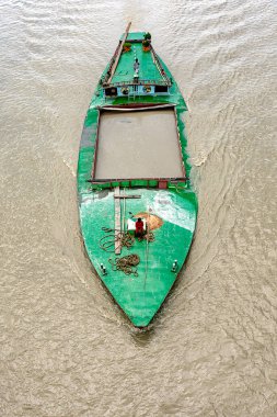 Bangladeş 'te bir nehirde yelken açan bir kum kargo gemisinin havadan görünüşü, mürettebatın yeşil boyanmış güvertede çalışması. Gemi büyük miktarda kumla dolu, iç kısımlarda su yolu taşımacılığı, geleneksel nakliye yöntemleri..
