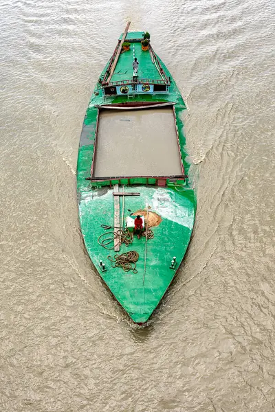 Bangladeş 'te bir nehirde yelken açan bir kum kargo gemisinin havadan görünüşü, mürettebatın yeşil boyanmış güvertede çalışması. Gemi büyük miktarda kumla dolu, iç kısımlarda su yolu taşımacılığı, geleneksel nakliye yöntemleri..