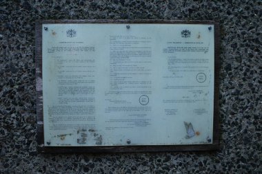 Taş bir duvarda saat resmi olan bir plaket.