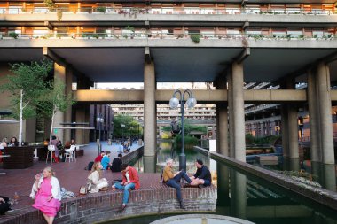 Nehrin kenarındaki bankta oturan bir grup insan.