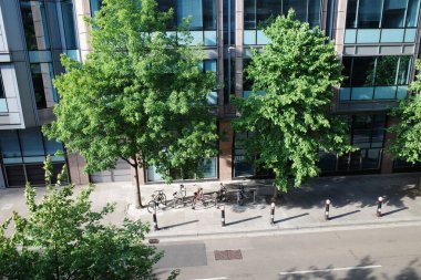 Bir grup insan yüksek bir binanın yanındaki sokakta yürüyor.