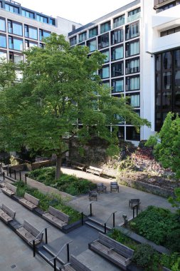 Binanın önündeki bankları ve ağaçları olan bir avlu.