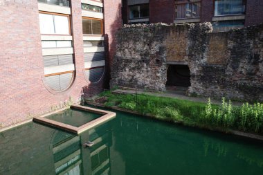 Önünde havuz olan tuğla bir bina.